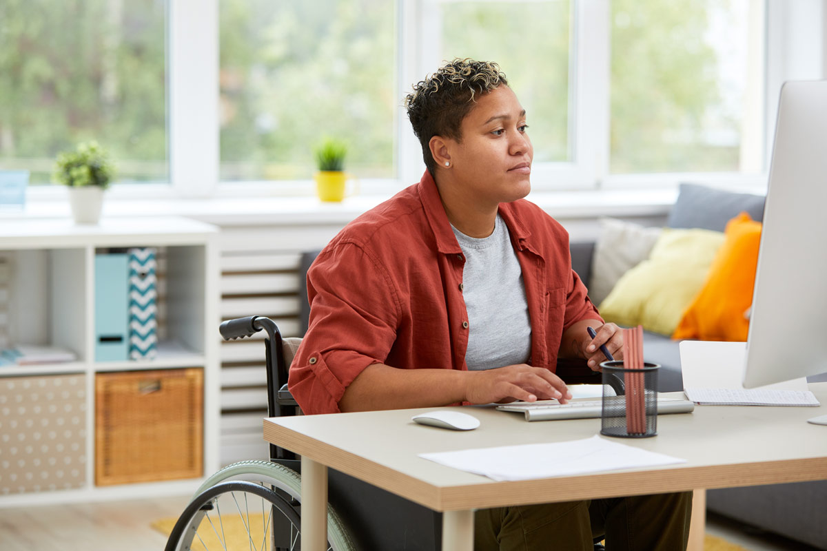 Serious disabled woman concentrating on her work she sitting at her workplace and working on computer at office