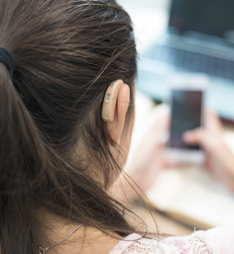 Girl with hearing aid studying and use mobile phone